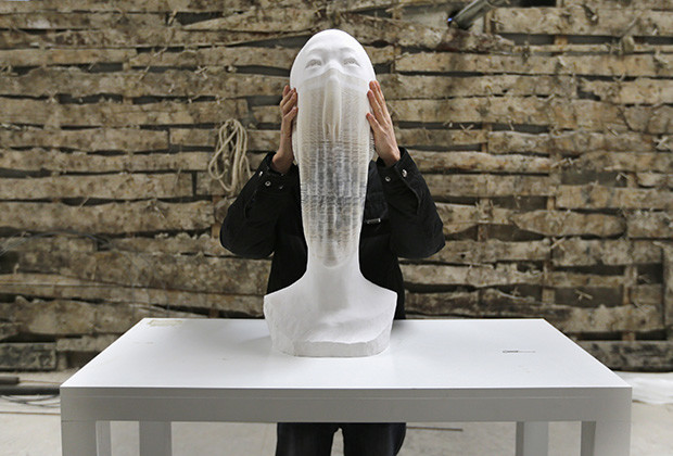 Li shows his paper sculpture work, which is made of 6,000 pieces of paper, while raising it at his studio on the outskirts of Beijing