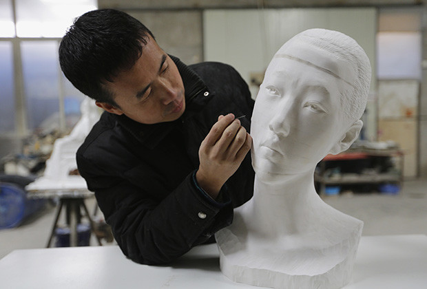 Chinese artist Li Hongbo uses an iron needle to remove dust from a paper sculpture work on the outskirts of Beijing